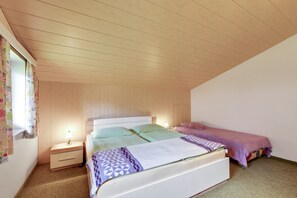 A bedroom with two beds, a nightstand, a lamp, and a window with curtains. - Spacious Apartment in Afritz am See near Ski Area (Treffen)