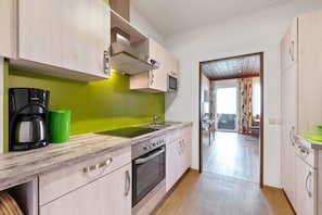 A modern kitchen with wooden cabinets, a built-in microwave, and a stainless steel oven.
