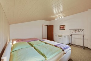 A bedroom with a bed, a wardrobe, a radiator, and a coat rack.