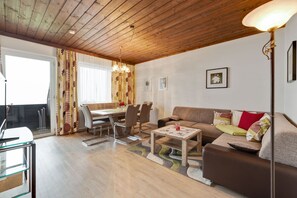 A living room with a wooden ceiling, a sofa, a coffee table, a dining table with chairs, and a lamp. - Spacious Apartment in Afritz am See near Ski Area (Treffen)