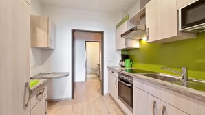 Eine moderne Küche mit Holzschränken, einer Edelstahl-Spüle und einer grünen Spritzschutzwand.