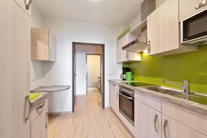 A modern kitchen with wooden cabinets, a stainless steel sink, and a green backsplash. - Spacious Apartment in Afritz am See near Ski Area (Treffen)