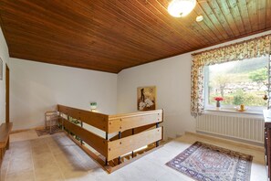 Una habitación con un banco de madera, un radiador, una ventana con vistas y una alfombra estampada.