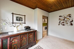 Ein Zimmer mit Holzboden, einem dekorativen Schrank mit einer alten Schreibmaschine, einem gerahmten Foto und einem Wandbild.