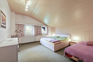 Ein Schlafzimmer mit einem Bett, einem Nachttisch, einer Lampe und einem Fenster mit Vorhängen.