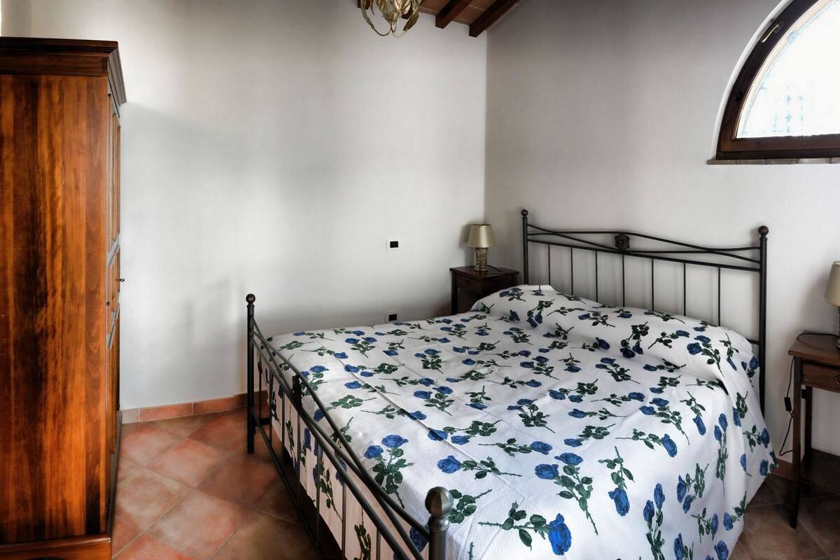 A bedroom with a bed, wooden wardrobe, and a window.