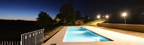 A swimming pool at dusk with surrounding trees and a small building. - Le Case (Pietralunga)
