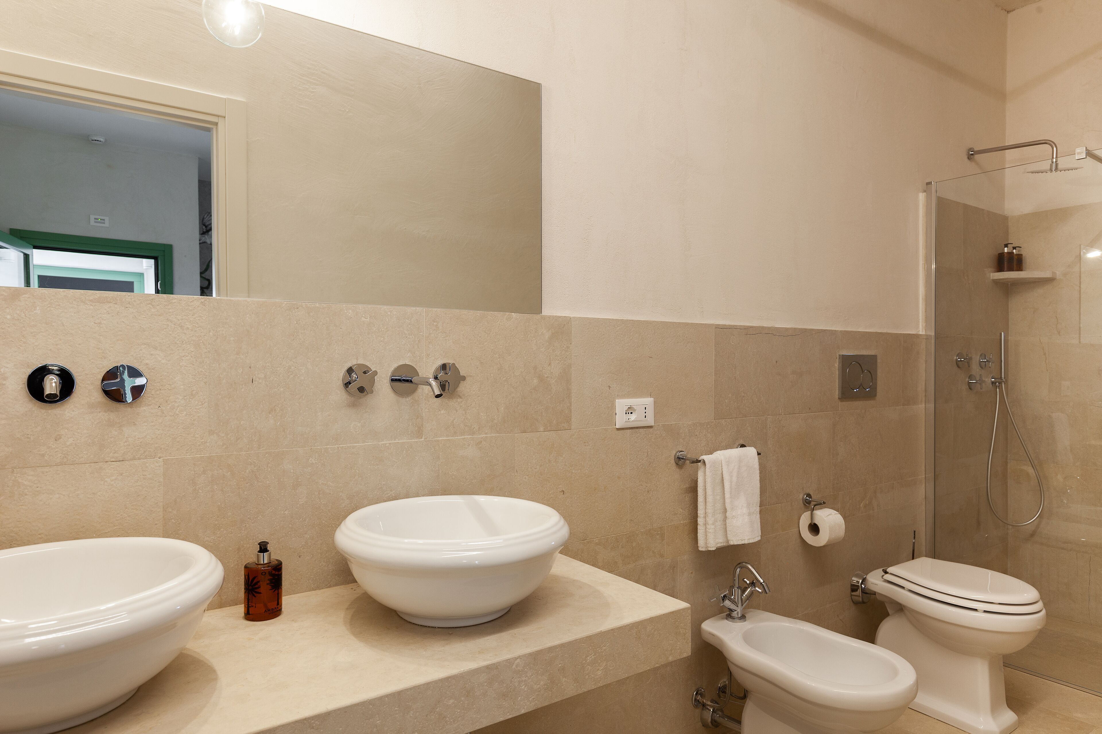 A modern bathroom with two sinks, a toilet, and a shower.