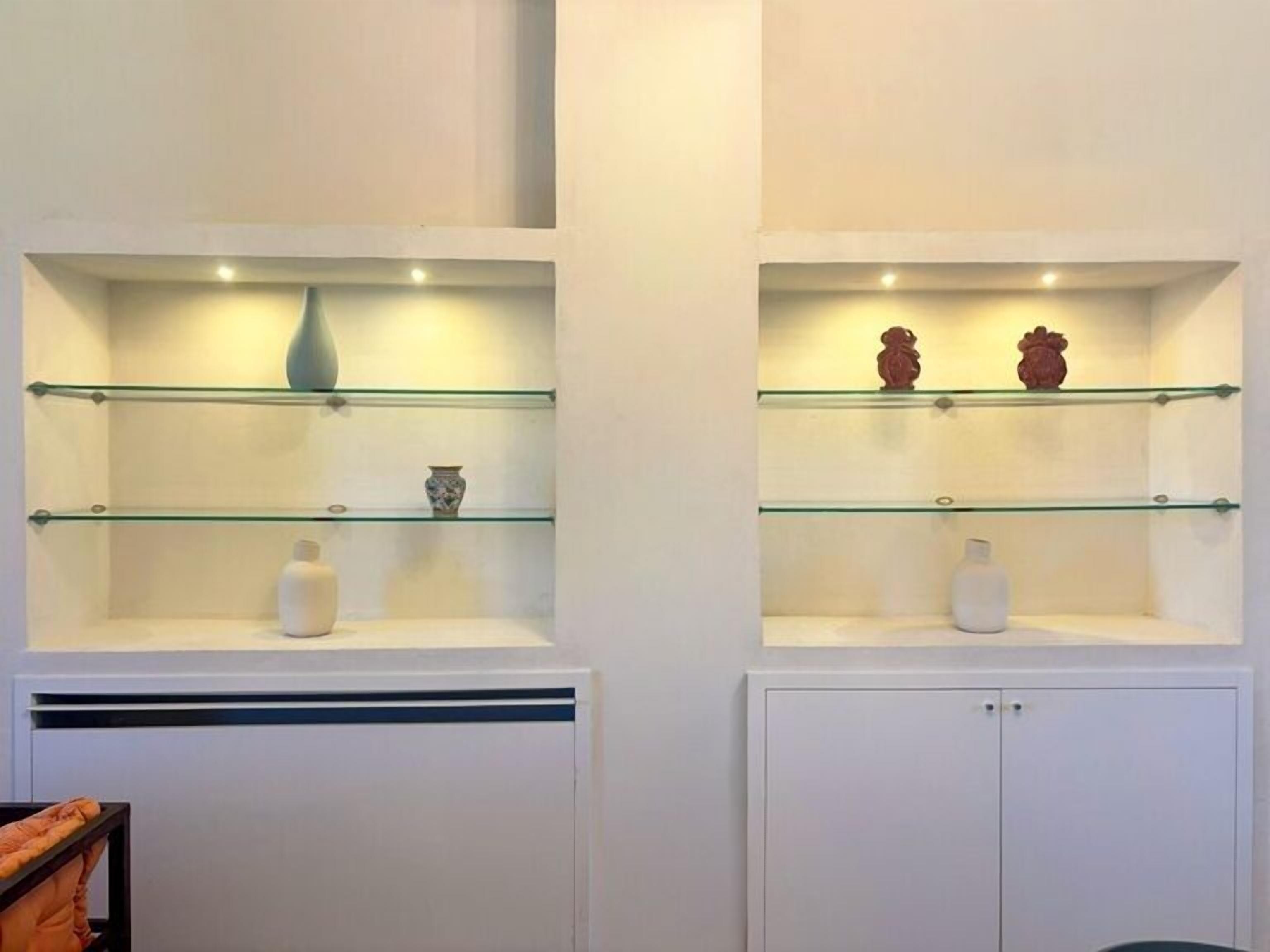 Two wall-mounted shelving units with glass shelves, each containing a few decorative items.