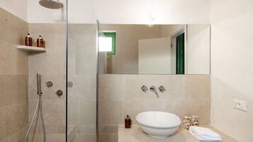 Een moderne badkamer met een douchecabine van glas, een grote spiegel en een wastafel met een witte wasbak.