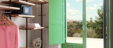 A room with a green door, a black cabinet, and wooden shelves with various items.