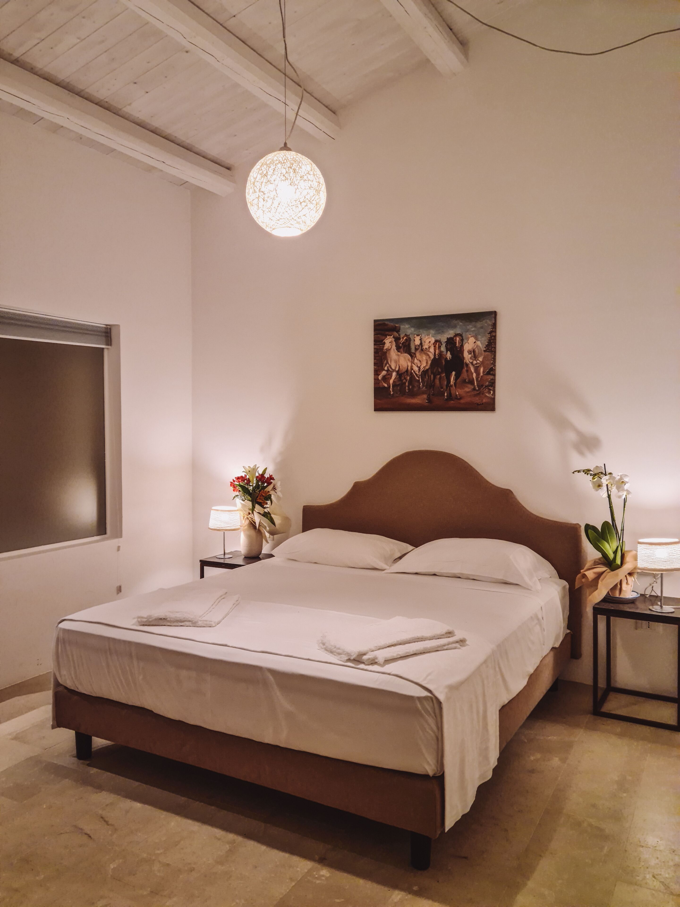 Un dormitorio con una cama grande, un cuadro en la pared, una mesita de noche con una lámpara y un candelabro.