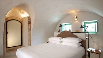 A bedroom with a bed, a nightstand, a lamp, and a window with a view.