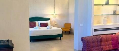 A room with a bed, a sofa, a small table, and a shelf with decorative items.