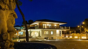 A two-story building with a balcony, a covered entrance, and a well-lit driveway. - Aurum Suites (Pescara)