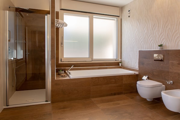 Un baño moderno con ducha de vidrio, bañera y retrete.