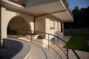 Un edificio moderno con una escalera curva, asientos exteriores y un césped bien cuidado.