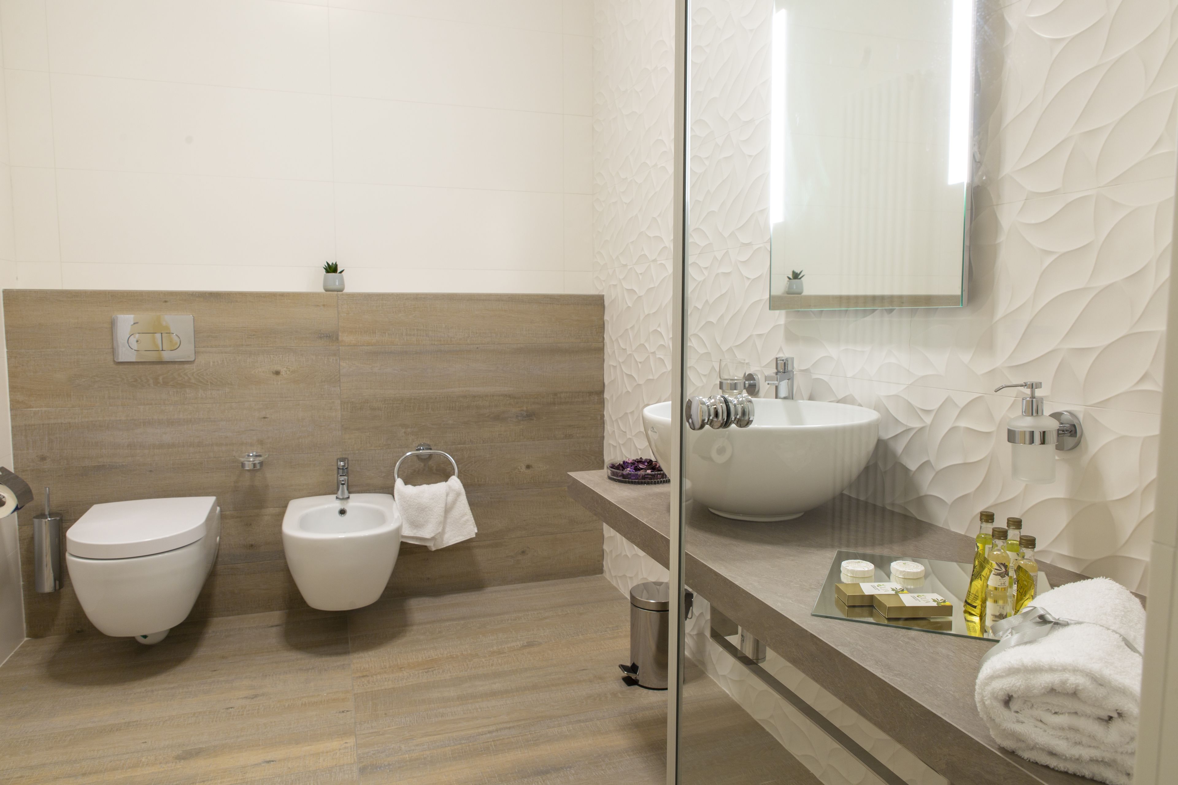 Een moderne badkamer met een bidet, een wastafel en een douchecabine van glas.