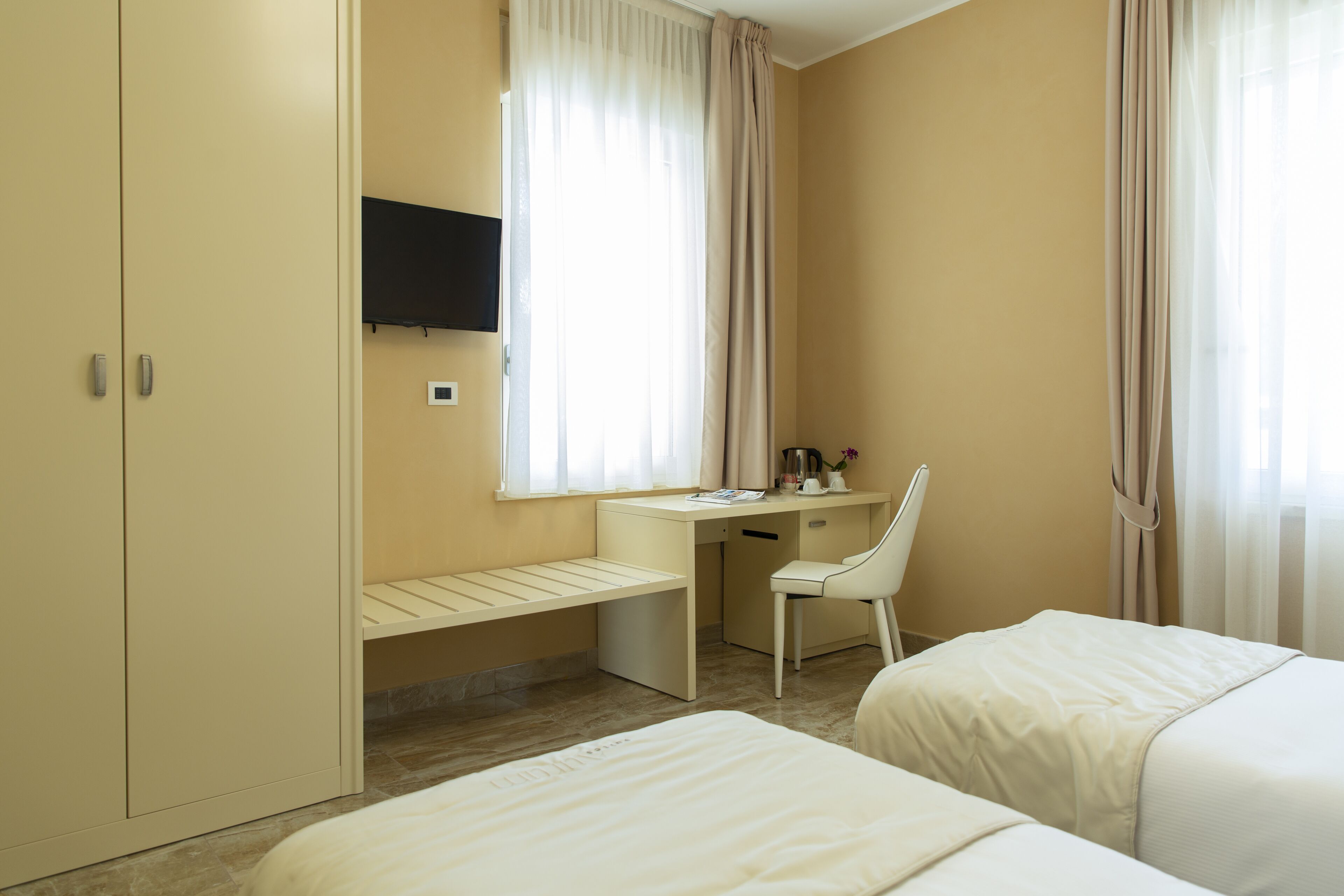 A hotel room with a bed, a desk, a chair, and a wardrobe.