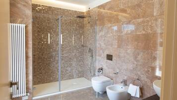 A modern bathroom with a walk-in shower, a bidet, a toilet, and a sink.