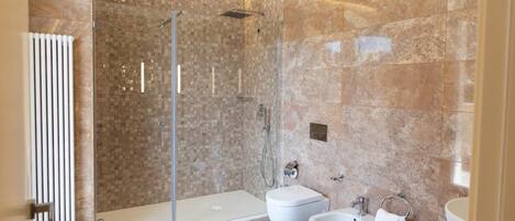 Une salle de bain moderne dotée d’une douche à l’italienne, d’un bidet, de toilettes et d’un lavabo.
