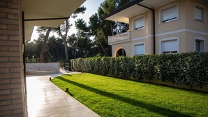 A modern building with a well-maintained lawn, a brick pathway, and a balcony with a railing. - Aurum Suites (Pescara)
