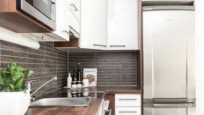 Una cocina moderna con un refrigerador de acero inoxidable, un lavamanos con grifo y una planta en maceta sobre la encimera.