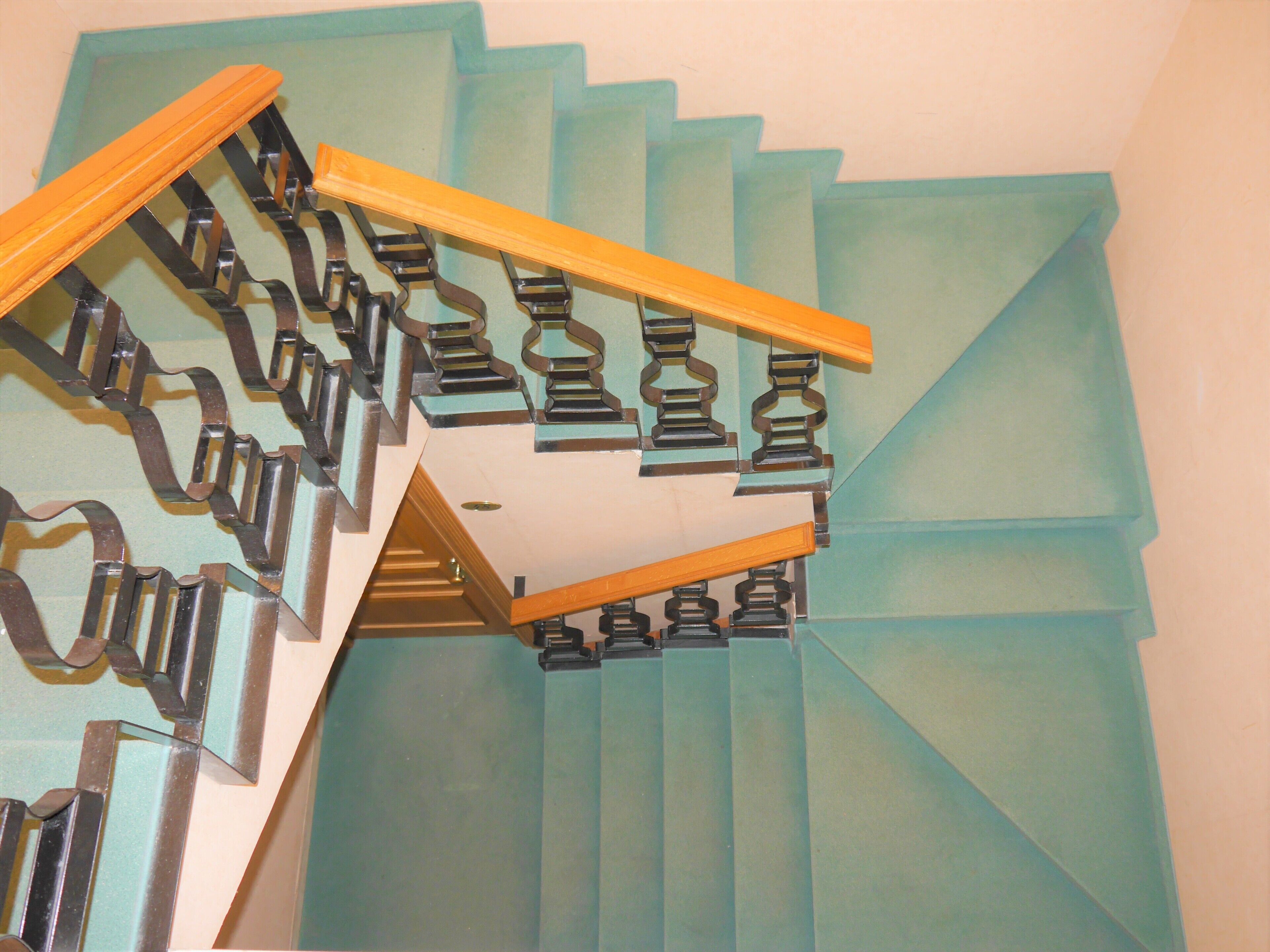 A spiral staircase with a wooden handrail and metal balusters.