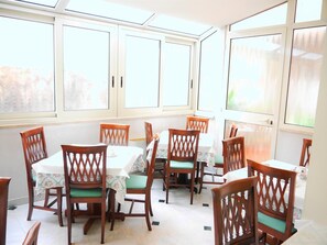 A dining area with wooden chairs and tables, large windows, and a skylight. - Hotel San Pietro (Rome)