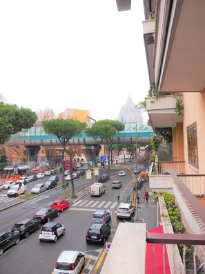 A busy urban street with cars, a pedestrian crossing, and a distinctive green bridge structure in the background. - Hotel San Pietro (Rome)