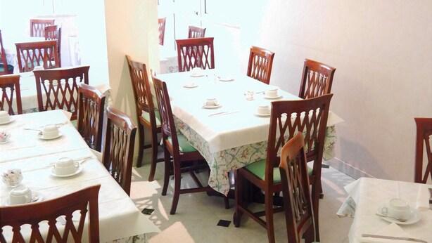 A dining area with multiple tables and chairs, a framed certificate on the wall, and a window providing natural light. - Hotel San Pietro (Rome)