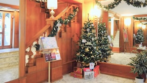 A Christmas decorated room with a staircase, a Christmas tree, and presents. - Hotel San Pietro (Rome)