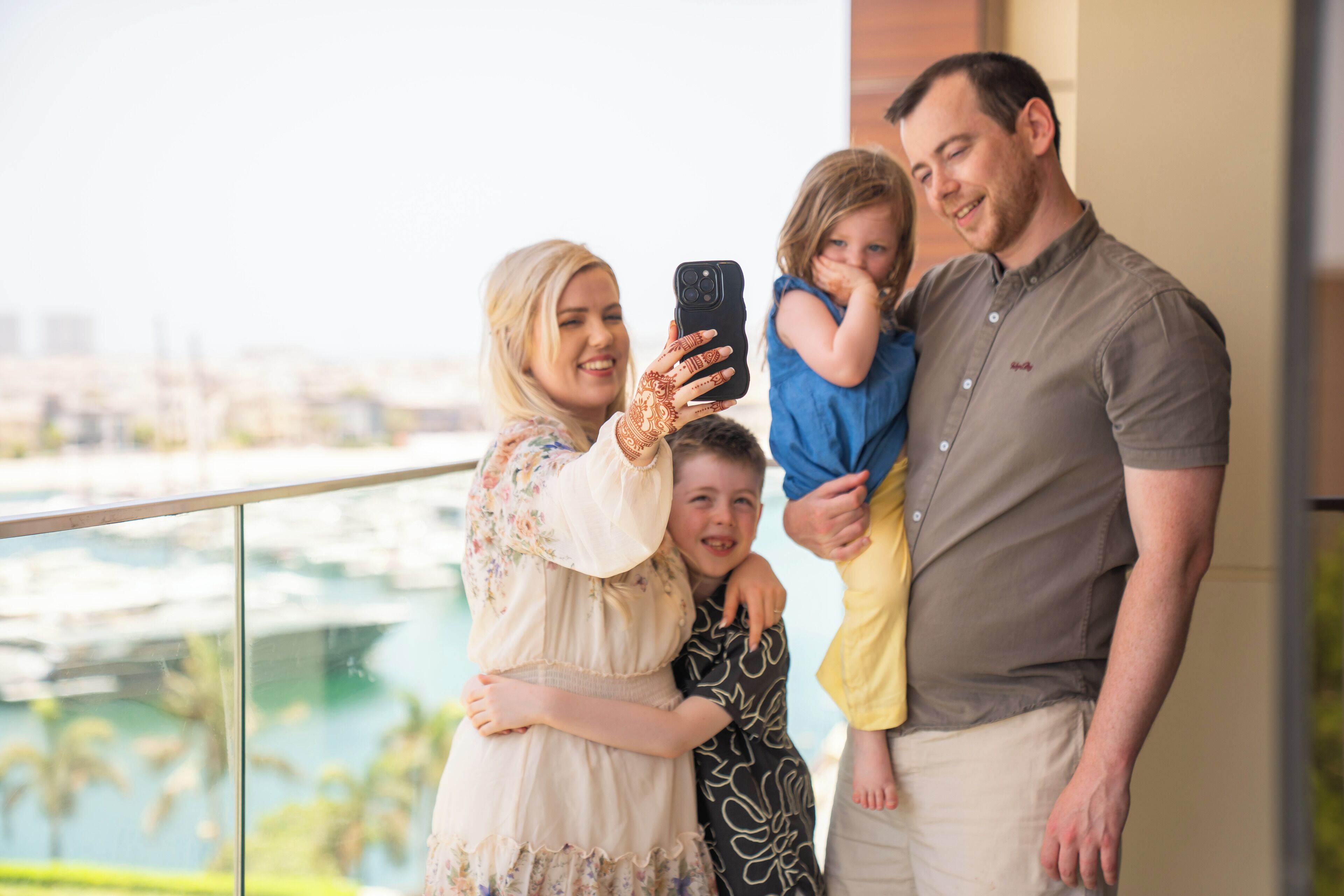 Une famille de quatre personnes sur un balcon, avec vue sur le paysage urbain.