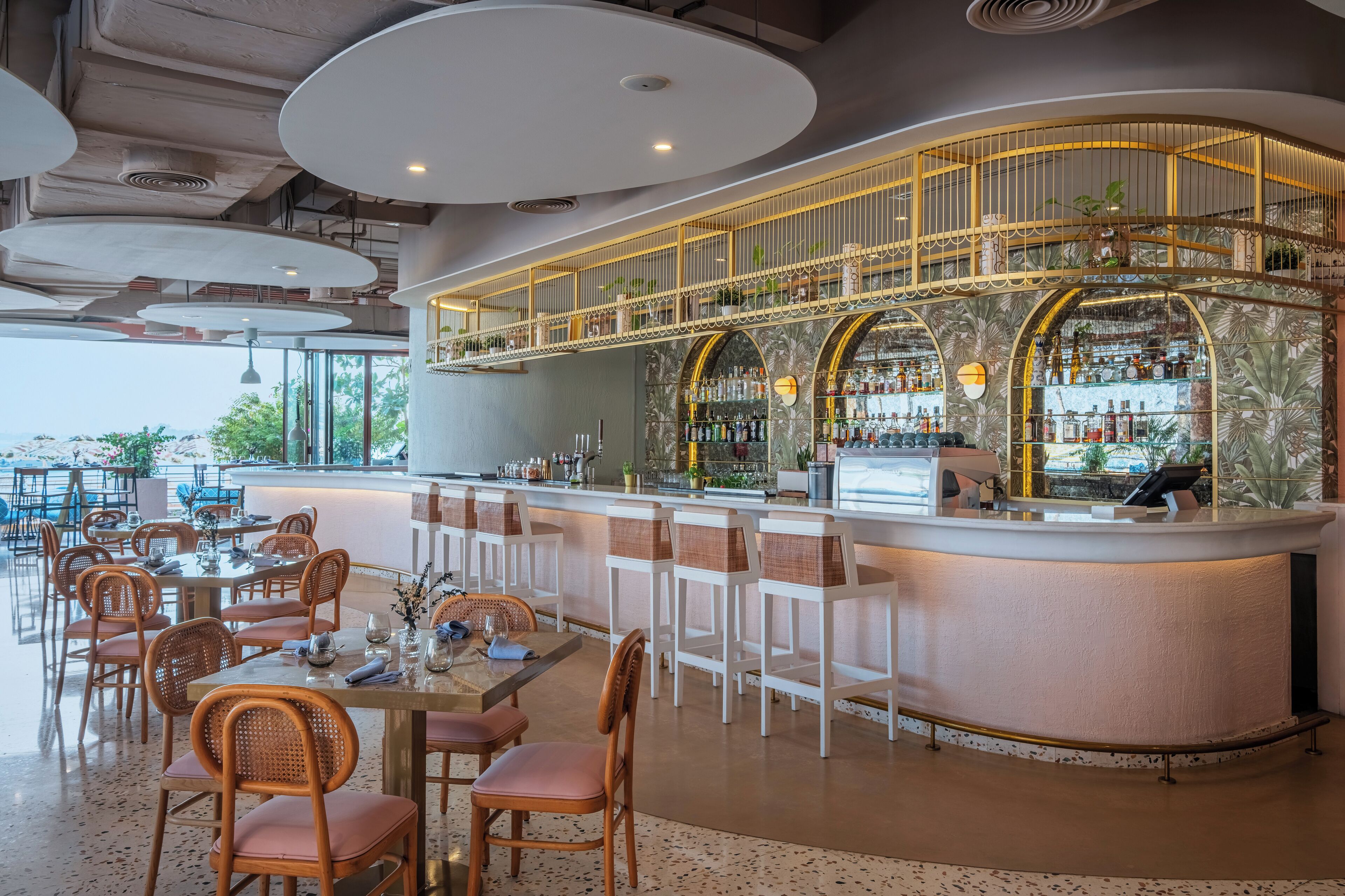 A modern bar area with a curved counter, multiple seating options, and a view of the outdoors.