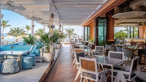 A rooftop bar with outdoor seating, a pool, and palm trees.