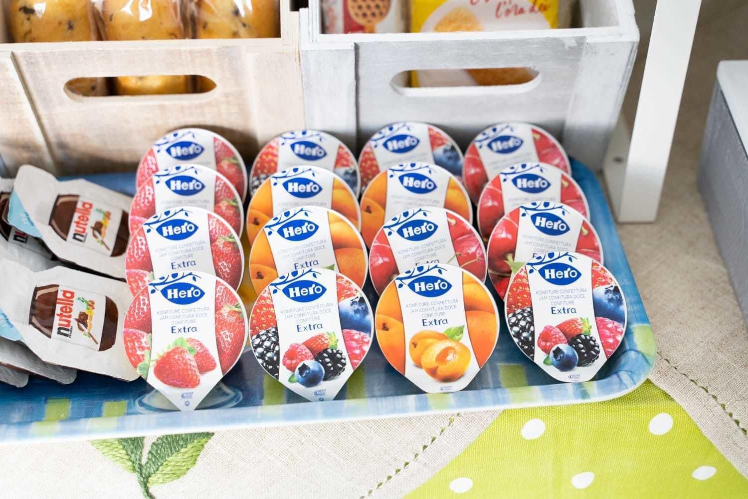 A display of Hero Extra yogurt cups in various flavors, arranged on a table with a colorful tablecloth.