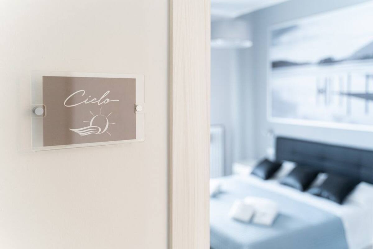 A hotel room with a bed, a bedside table, and a window with a view of a body of water.