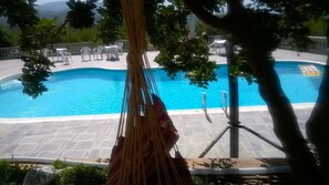 Una piscina al aire libre de temporada, sombrillas, tumbonas