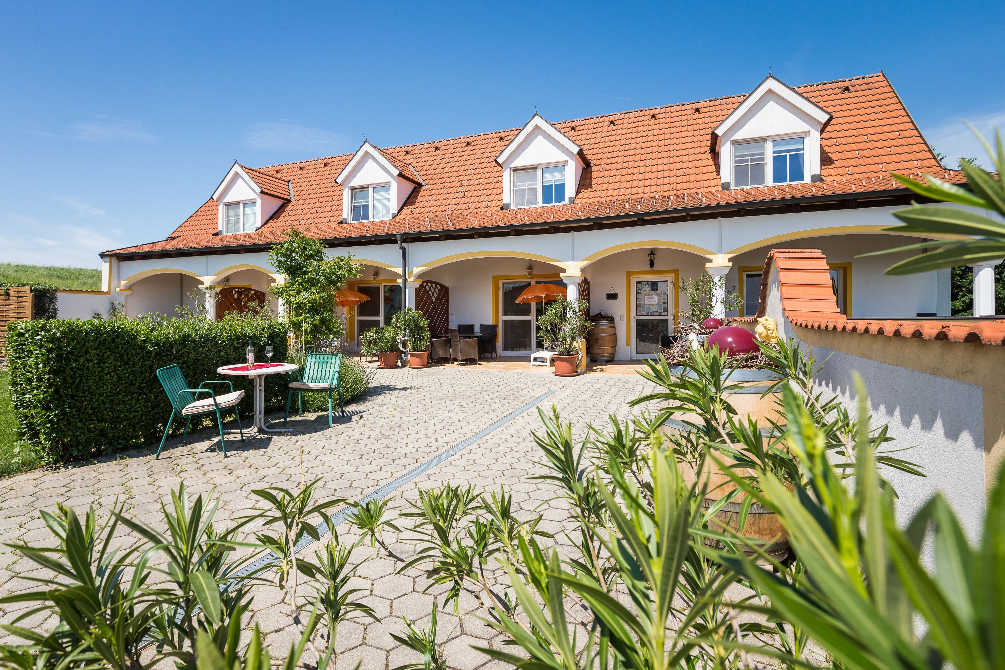 A two-story building with a tiled roof and a covered patio area.