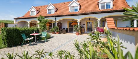 A two-story building with a tiled roof and a covered patio area.