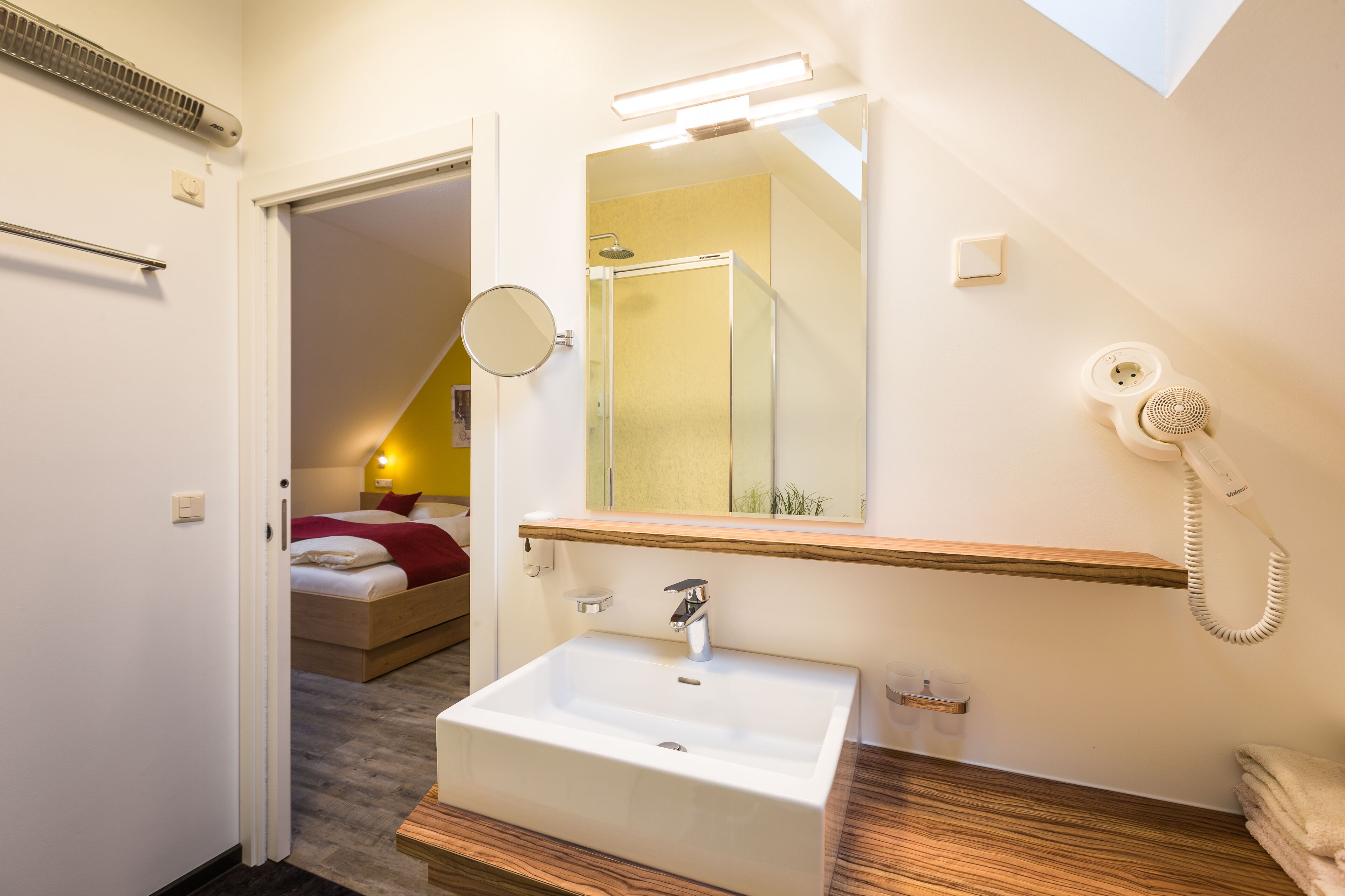 A modern bathroom with a white sink, a mirror, and a shower.