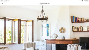 A cozy living room with a fireplace, striped armchairs, a dining table, and a bookshelf. - Villa on the sea in Punta Tramontana with an exclusive view of the Gulf of Asinara (Punta Tramontana (Castelsardo))