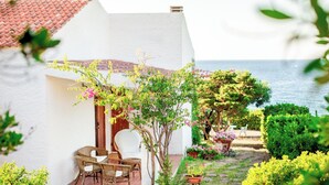 A white building with a tiled roof, a patio with wicker furniture, and potted plants. - Villa on the sea in Punta Tramontana with an exclusive view of the Gulf of Asinara (Punta Tramontana (Castelsardo))