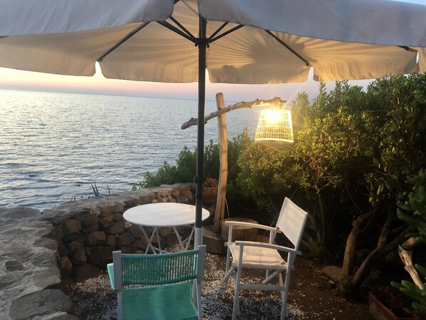 Relax by the sea with a table and two chairs under a shaded area.