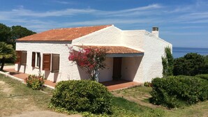 A white building with a red-tiled roof, a small porch, and a view of the sea. - Villa on the sea in Punta Tramontana with an exclusive view of the Gulf of Asinara (Punta Tramontana (Castelsardo))