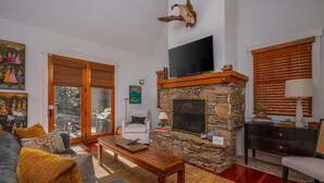 A living room with a stone fireplace, a flat-screen TV, a sofa, and a dining table. - Mountain Gem I Pet Friendly Luxury Cottage in Cheshire Village (Black Mountain)