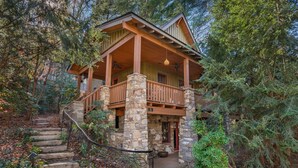 A rustic cabin with a stone staircase leading to a wooden deck, surrounded by dense forest. - Mountain Gem I Pet Friendly Luxury Cottage in Cheshire Village (Black Mountain)