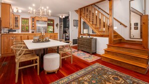 A spacious kitchen with wooden cabinets, a stainless steel refrigerator, and a chandelier. - Mountain Gem I Pet Friendly Luxury Cottage in Cheshire Village (Black Mountain)