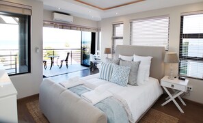 Un dormitorio con una cama grande, mesitas de noche y vistas al balcón.