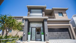 A modern two-story house with a garage, large windows, and a balcony. - C' la Vie Melkbos (Cape Town)